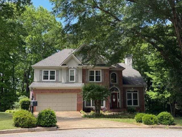traditional-style home featuring concrete driveway, a chimney, and an attached garage