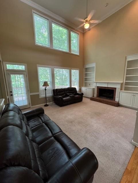 living area with ceiling fan, a wealth of natural light, a towering ceiling, and ornamental molding