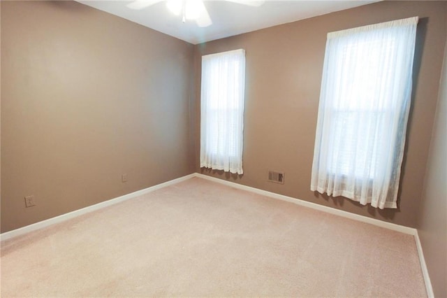 spare room featuring visible vents, baseboards, ceiling fan, and light carpet