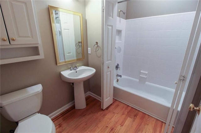 full bath featuring toilet, washtub / shower combination, baseboards, and wood finished floors