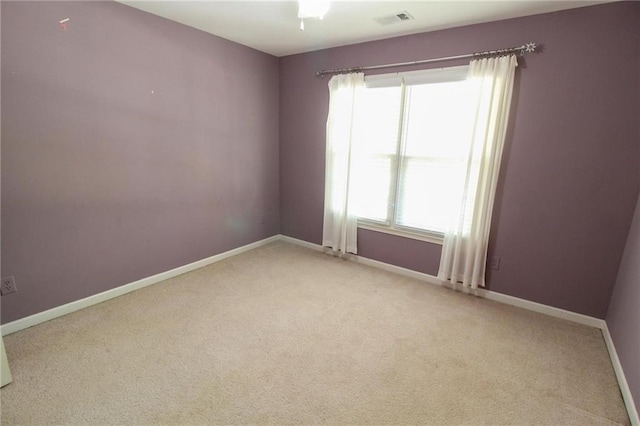 spare room featuring baseboards, light carpet, and visible vents