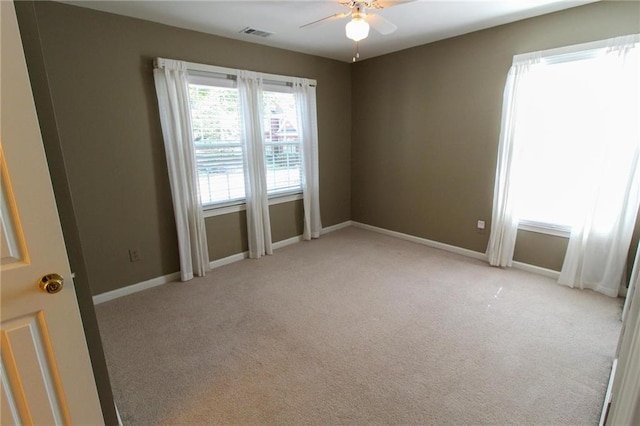 spare room with ceiling fan, light carpet, baseboards, and visible vents
