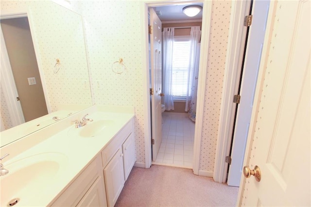 full bathroom featuring baseboards, wallpapered walls, a sink, and double vanity