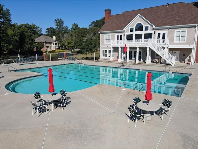 community pool featuring a patio area, fence, and stairs