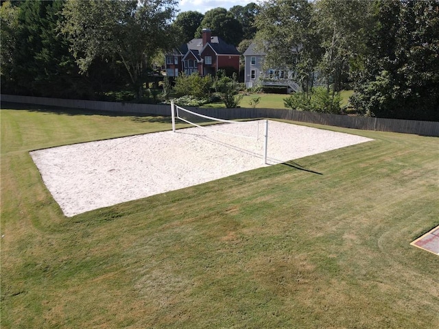 view of home's community with fence, a lawn, and volleyball court