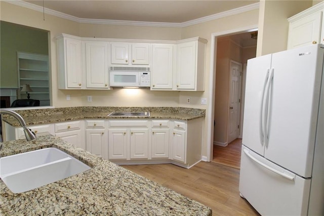 kitchen with a sink, white cabinets, light wood-type flooring, white appliances, and light stone counters