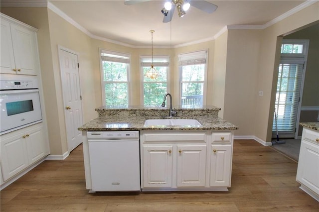 kitchen with baseboards, white appliances, ceiling fan, a sink, and light wood-type flooring