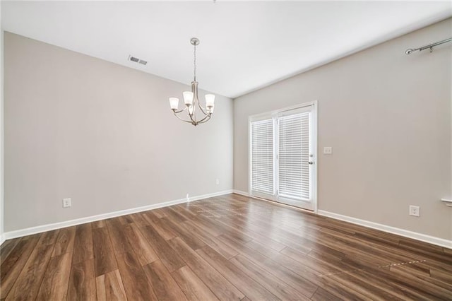 unfurnished room with a chandelier, wood finished floors, and baseboards