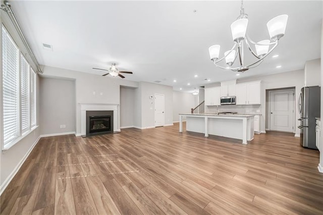 unfurnished living room with ceiling fan, wood finished floors, baseboards, a glass covered fireplace, and recessed lighting