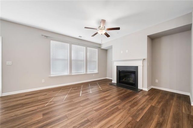 unfurnished living room featuring a ceiling fan, wood finished floors, a glass covered fireplace, and baseboards