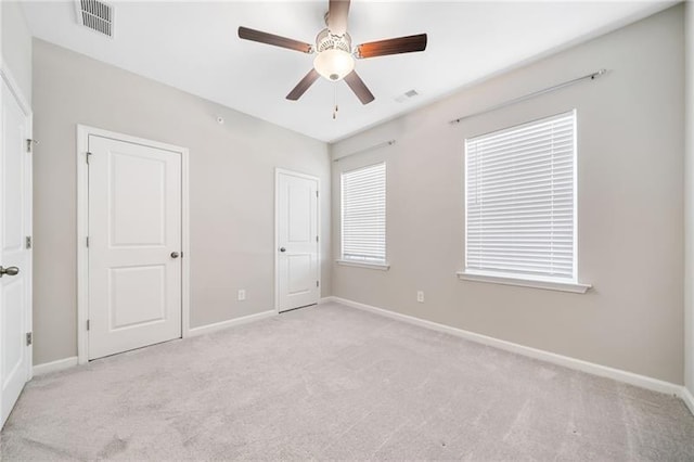 unfurnished bedroom with light colored carpet, baseboards, and a ceiling fan