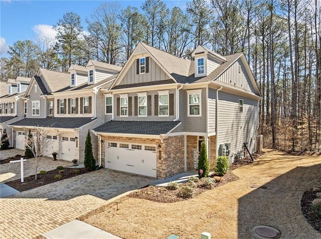 view of front of house featuring an attached garage, board and batten siding, driveway, and stone siding