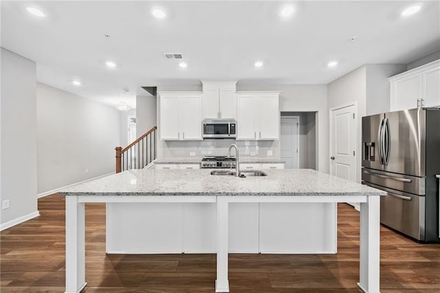 kitchen with appliances with stainless steel finishes, a sink, dark wood-style flooring, decorative backsplash, and recessed lighting