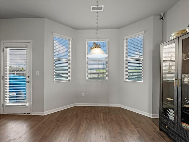 unfurnished dining area with baseboards, visible vents, and dark wood-style floors
