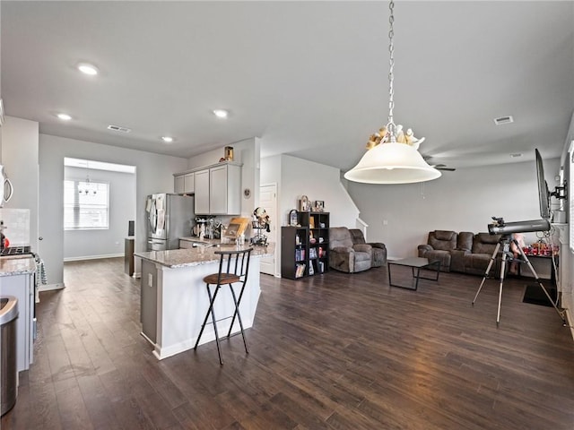 kitchen featuring stainless steel appliances, dark wood-style flooring, open floor plan, visible vents, and light stone countertops