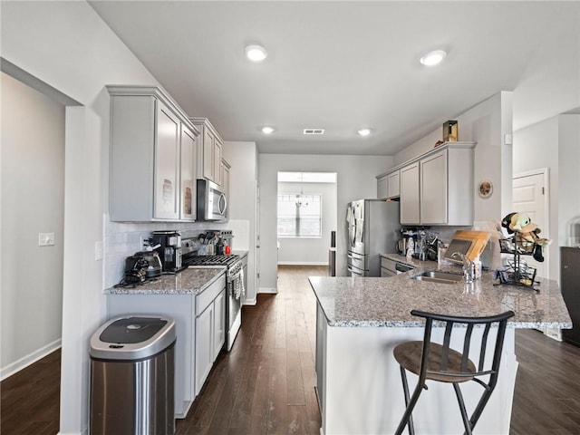 kitchen featuring a sink, stainless steel appliances, baseboards, gray cabinetry, and visible vents