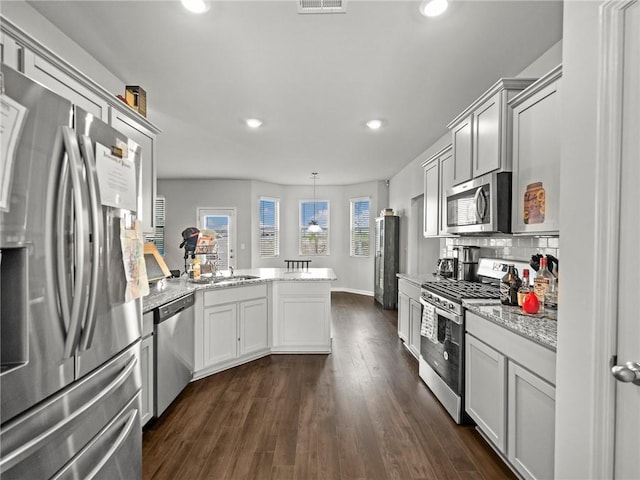 kitchen featuring recessed lighting, dark wood-style floors, stainless steel appliances, backsplash, and a peninsula