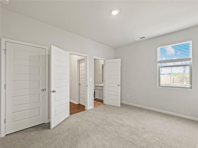 unfurnished bedroom with carpet, visible vents, baseboards, and connected bathroom