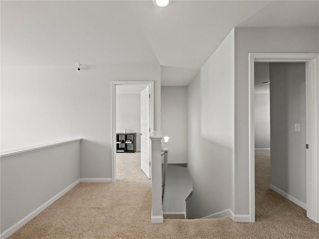 hallway featuring carpet floors, baseboards, and an upstairs landing