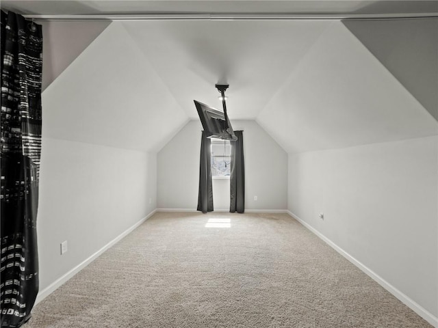 additional living space featuring carpet floors, vaulted ceiling, and baseboards