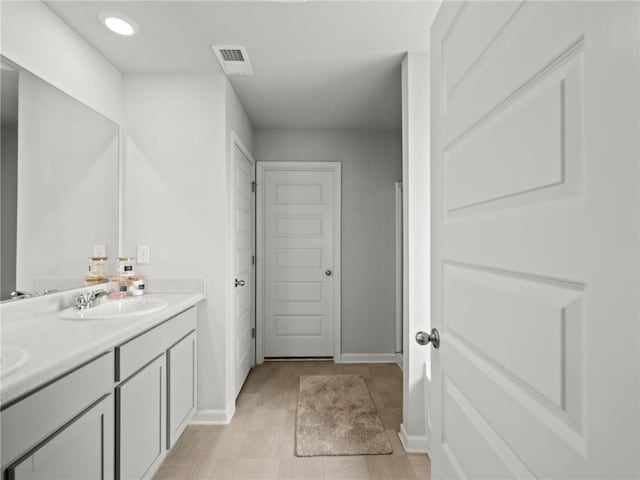 bathroom with recessed lighting, double vanity, visible vents, a sink, and baseboards