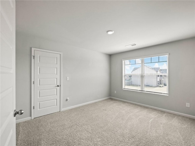 carpeted empty room with visible vents and baseboards