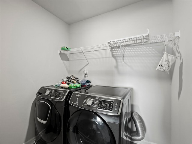 washroom featuring washing machine and clothes dryer, baseboards, and laundry area