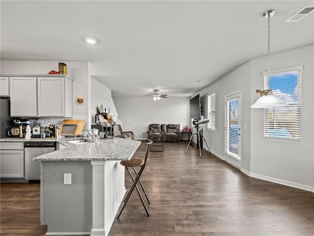 kitchen with a peninsula, stainless steel dishwasher, visible vents, a ceiling fan, and dark wood-type flooring