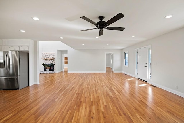 unfurnished living room with baseboards, light wood-style flooring, recessed lighting, ceiling fan, and a large fireplace