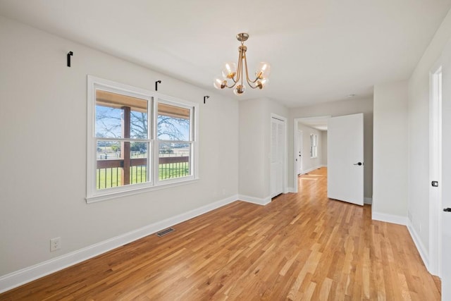 unfurnished room featuring light wood-style flooring, baseboards, visible vents, and a chandelier