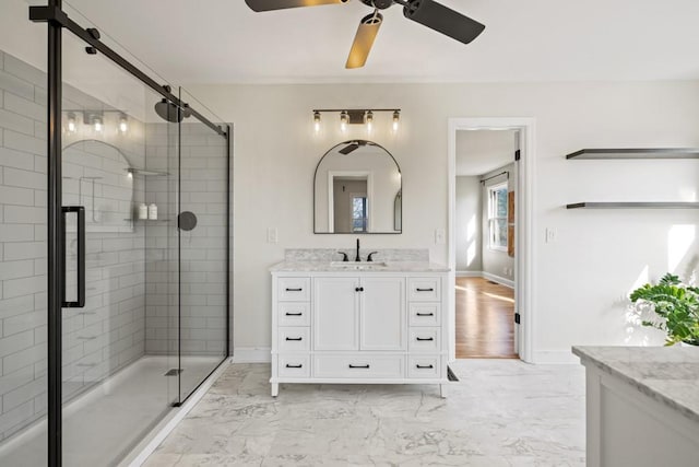 full bath featuring marble finish floor, a stall shower, a ceiling fan, baseboards, and vanity