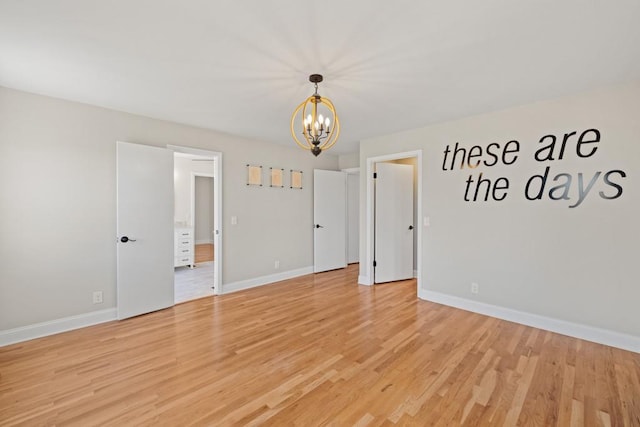 empty room featuring light wood-style floors, baseboards, and a chandelier