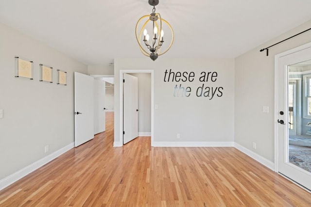 empty room with a chandelier, light wood-type flooring, and baseboards