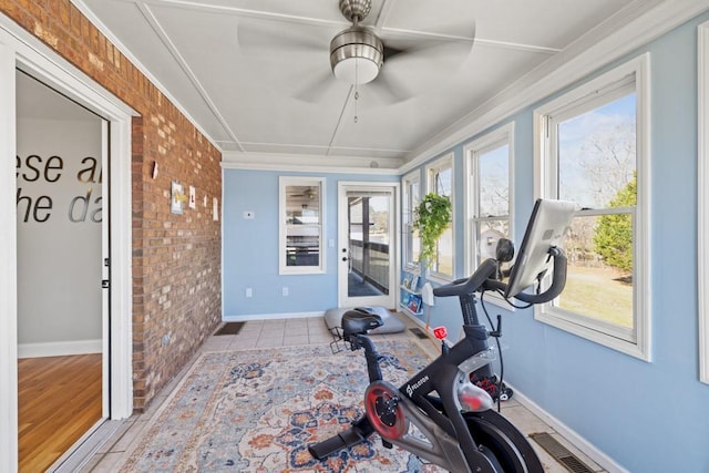 exercise room featuring baseboards, visible vents, and brick wall