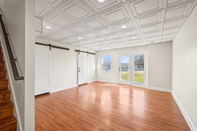 unfurnished living room featuring stairway, an ornate ceiling, baseboards, and a barn door