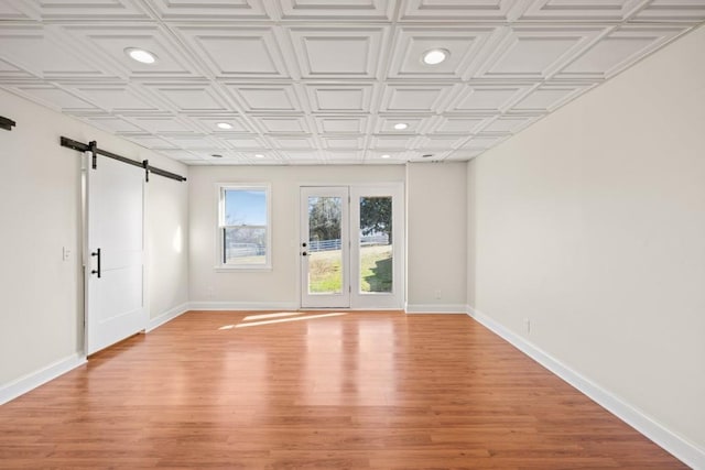 spare room featuring recessed lighting, a barn door, baseboards, and an ornate ceiling