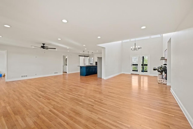 unfurnished living room featuring recessed lighting, visible vents, ceiling fan with notable chandelier, and light wood finished floors