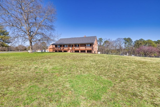 view of front of property featuring a wooden deck, a chimney, and a front yard