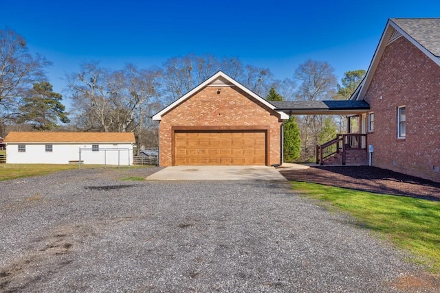 view of home's exterior featuring an attached garage, fence, brick siding, and driveway