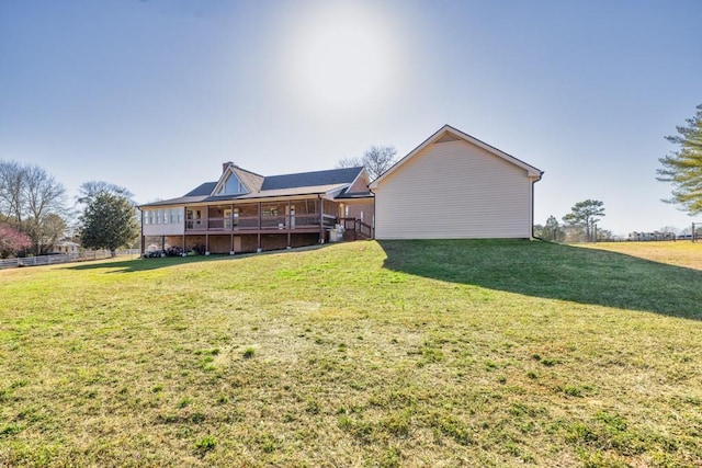 back of property featuring a lawn and fence