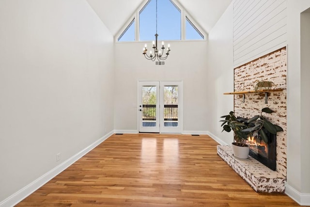 foyer entrance featuring a notable chandelier, a fireplace, visible vents, and light wood finished floors