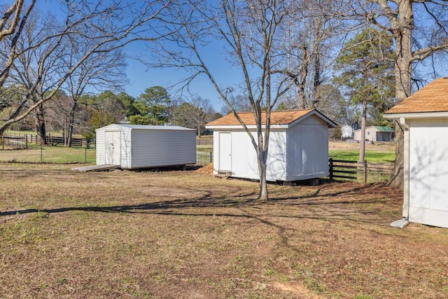 view of yard featuring a storage unit, an outdoor structure, and fence