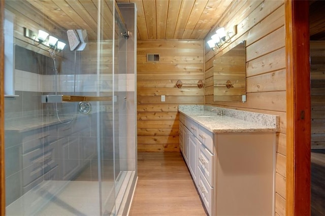 bathroom with vanity, a shower with shower door, wooden ceiling, and wood walls