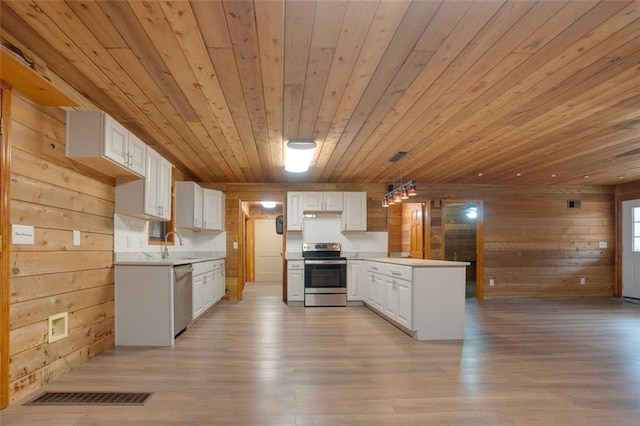 kitchen with appliances with stainless steel finishes, sink, decorative light fixtures, wooden ceiling, and white cabinetry