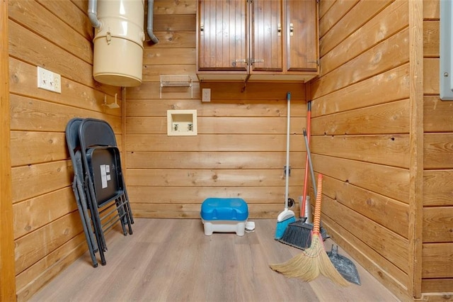 exercise room with wood walls and light wood-type flooring