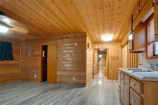 kitchen with wood walls, light wood-type flooring, wood ceiling, and sink