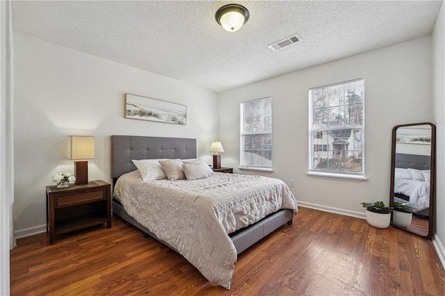 bedroom featuring a textured ceiling and dark hardwood / wood-style flooring