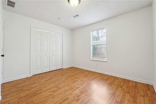 unfurnished bedroom featuring hardwood / wood-style flooring, a textured ceiling, and a closet