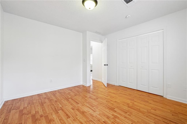 unfurnished bedroom with light hardwood / wood-style flooring and a closet