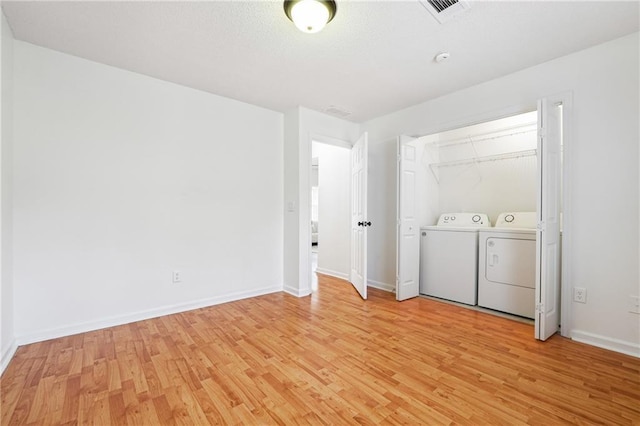 clothes washing area featuring washer and clothes dryer and light hardwood / wood-style floors